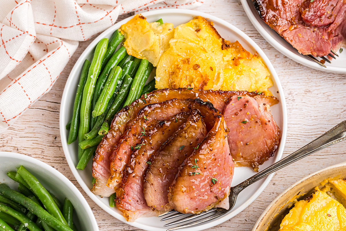 overhead shot of plate of sliced riesling peach glazed ham with veggies