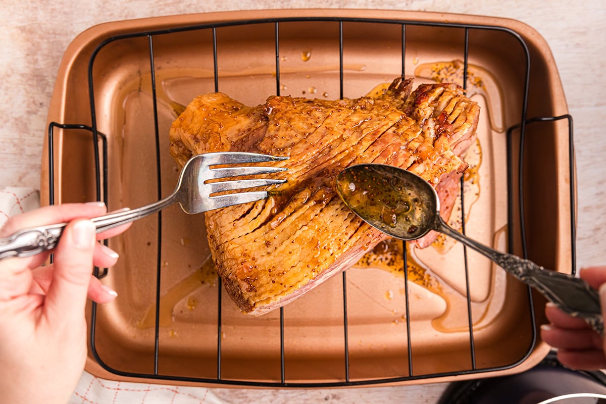 spoon adding glaze to sliced ham