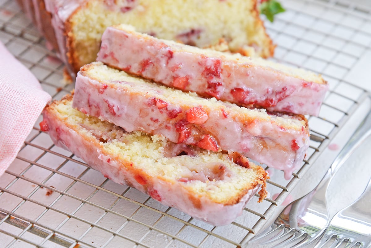 three slices of pound cake with strawberries on a wire rack