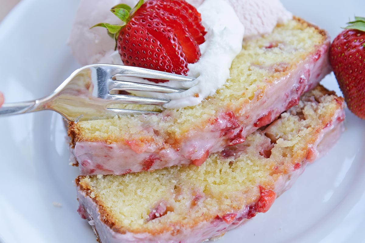 fork digging into a pound cake with strawberries