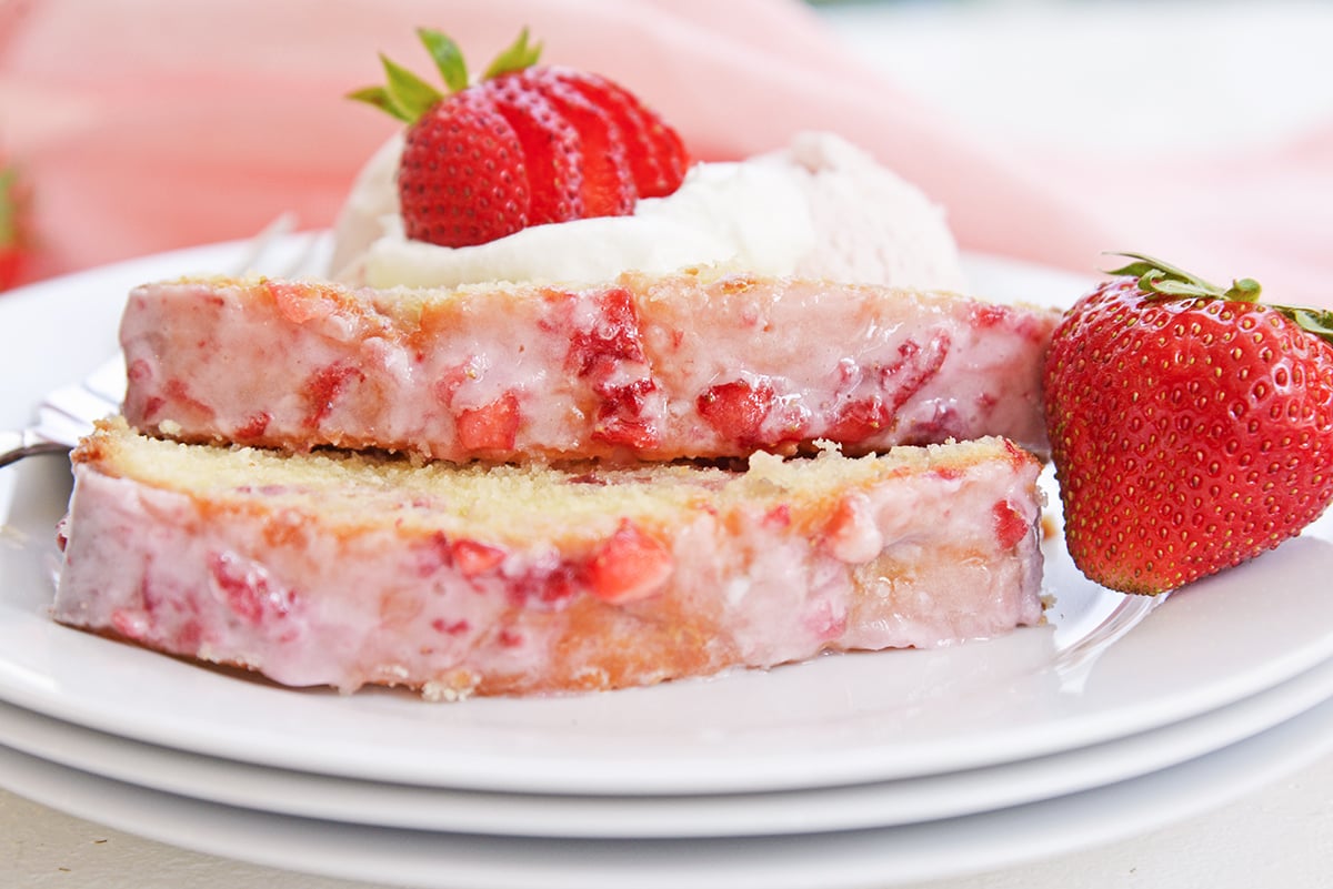 close up of serving plate with strawberry pound cake, whipped cream and and fresh strawberries