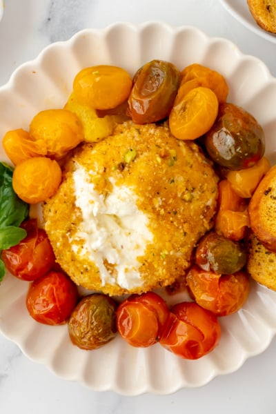 overhead shot of air fryer burrata on plate with tomatoes and garlic bread with scoop taken out