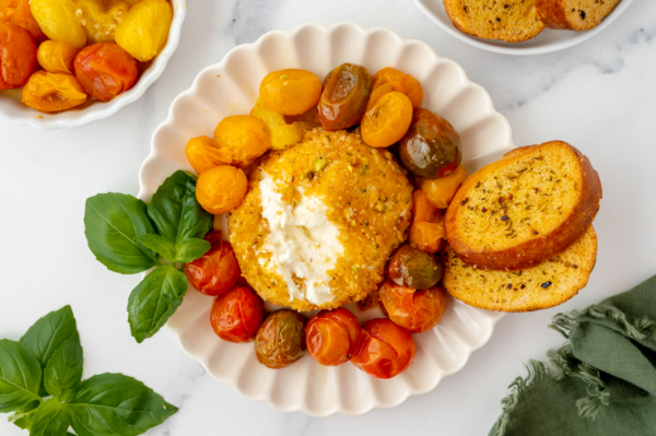 overhead shot of air fryer burrata on plate with tomatoes and garlic bread with scoop taken out