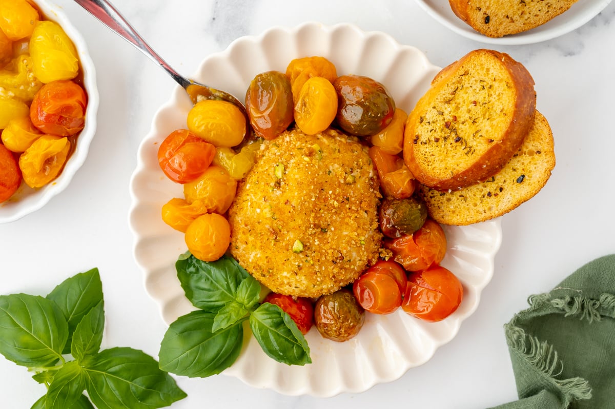 overhead shot of air fryer burrata on plate with tomatoes and garlic bread and spoon
