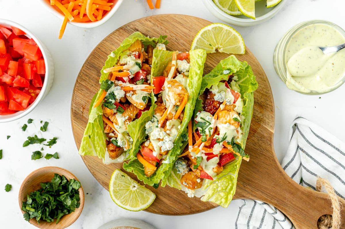 overhead shot of three bbq chicken lettuce wraps on a wooden board