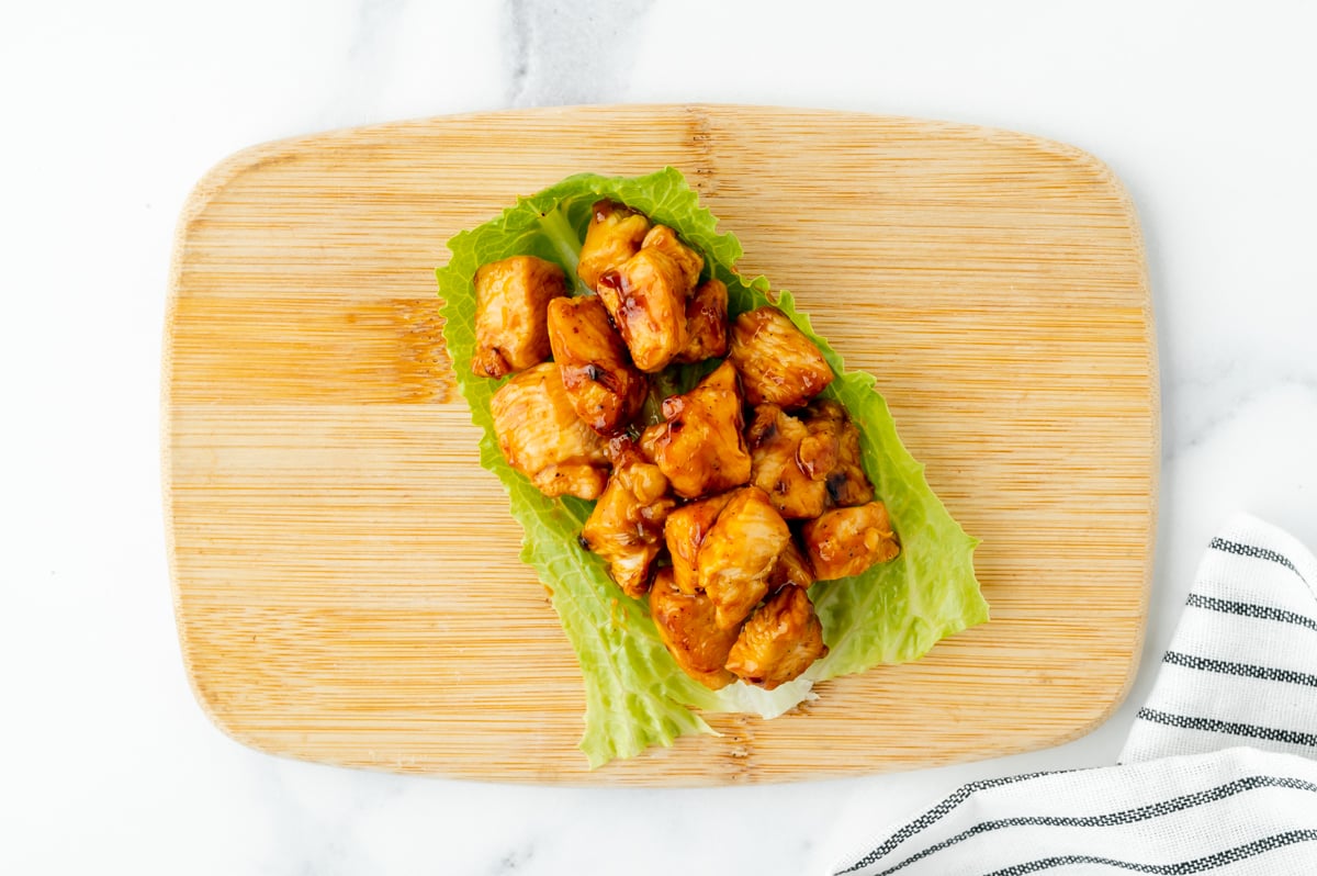 bbq chicken in lettuce wrap on wooden board