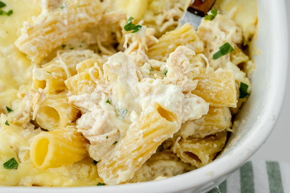 close up angled shot of scoop of chicken alfredo bake on serving spoon