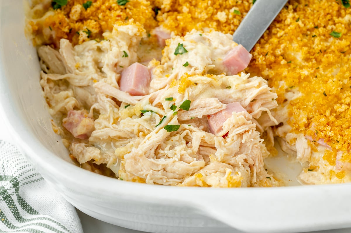 close up angled shot of serving spoon scooping up chicken cordon bleu casserole