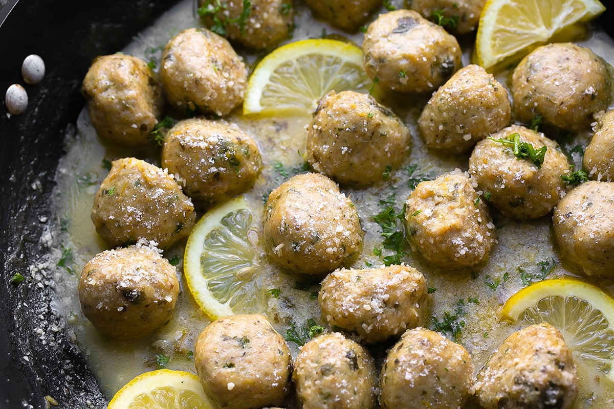 angled shot of chicken piccata meatballs in pan