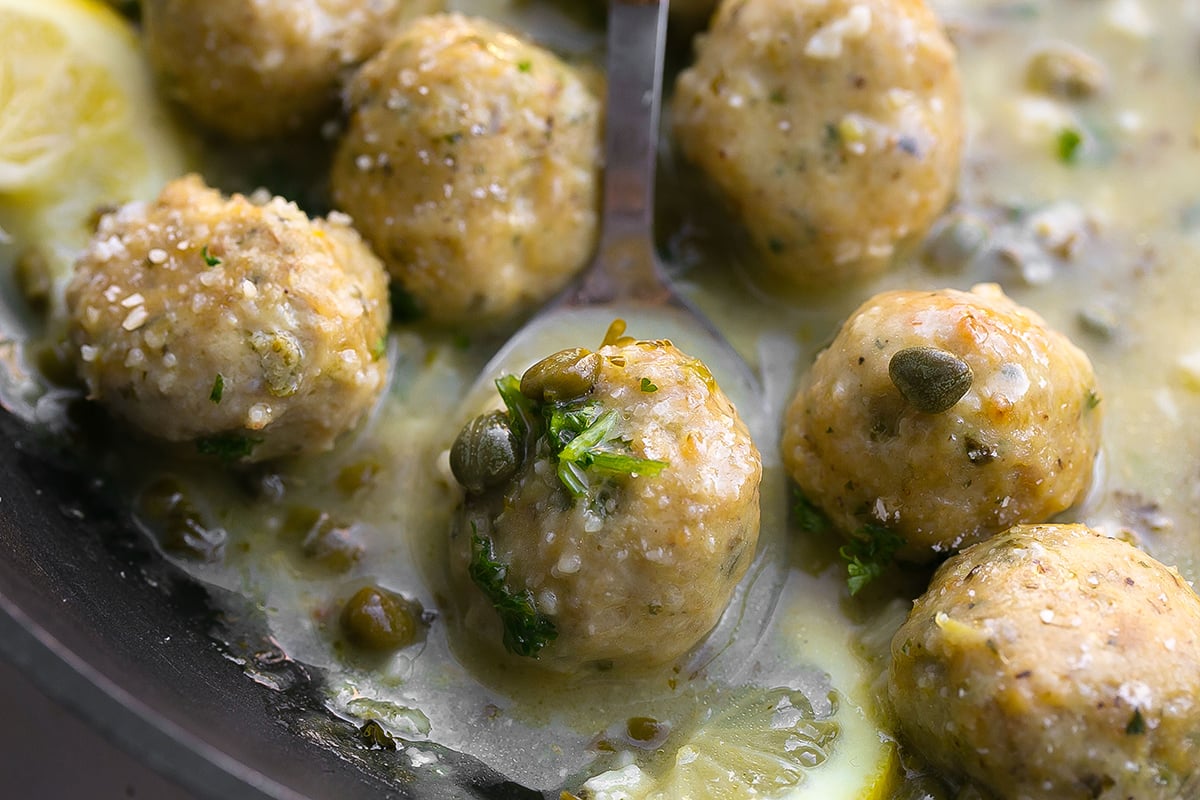 close up of spoon in pan of chicken piccata meatballs