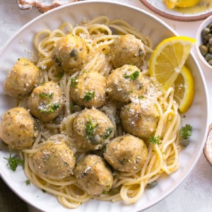 overhead shot of chicken piccata meatballs over pasta