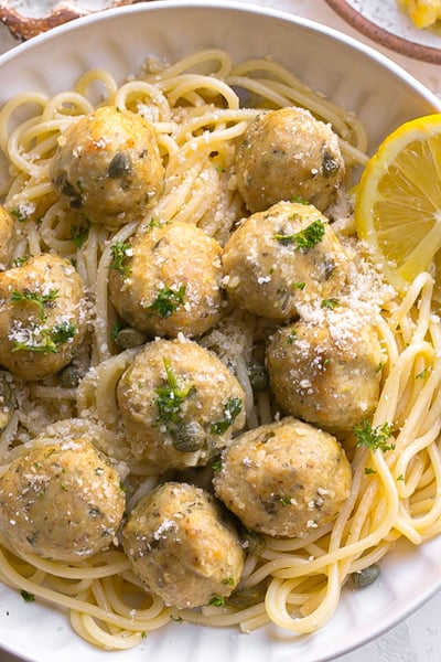 overhead shot of chicken piccata meatballs over pasta