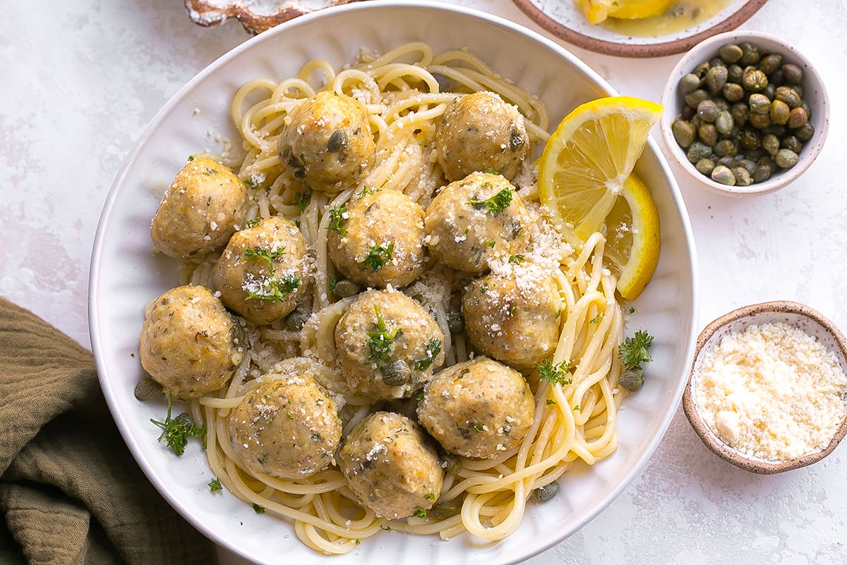 overhead shot of chicken piccata meatballs over pasta