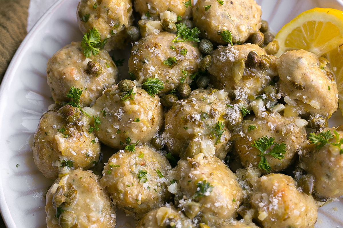 close up overhead shot of chicken piccata meatballs on white plate