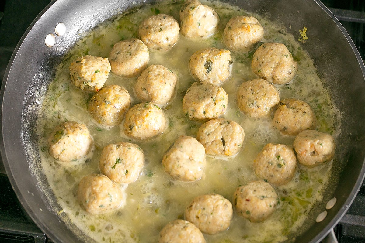 chicken meatballs simmering in pan of sauce