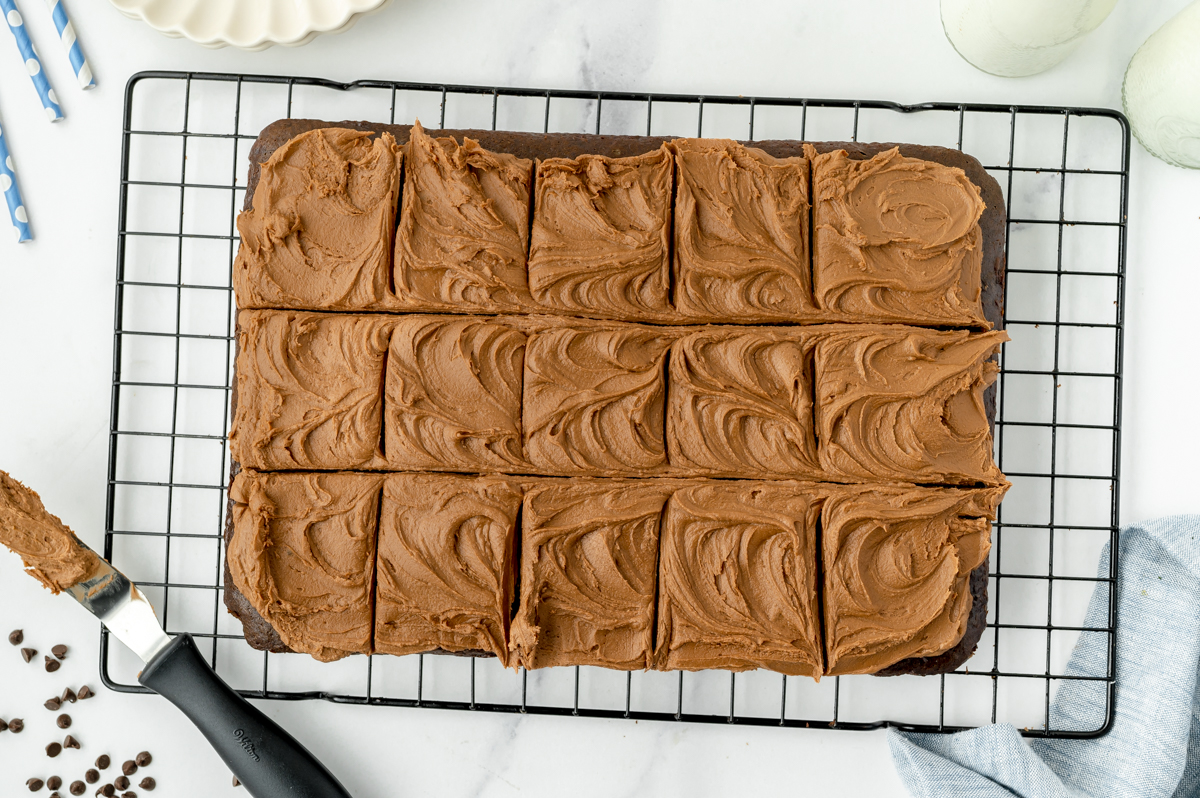 overhead shot of frosted and sliced mayonnaise chocolate cake on cooling rack