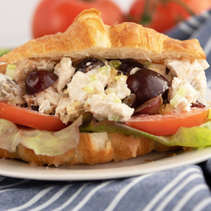 A close up of a sandwich on a plate, with Chicken and Salad