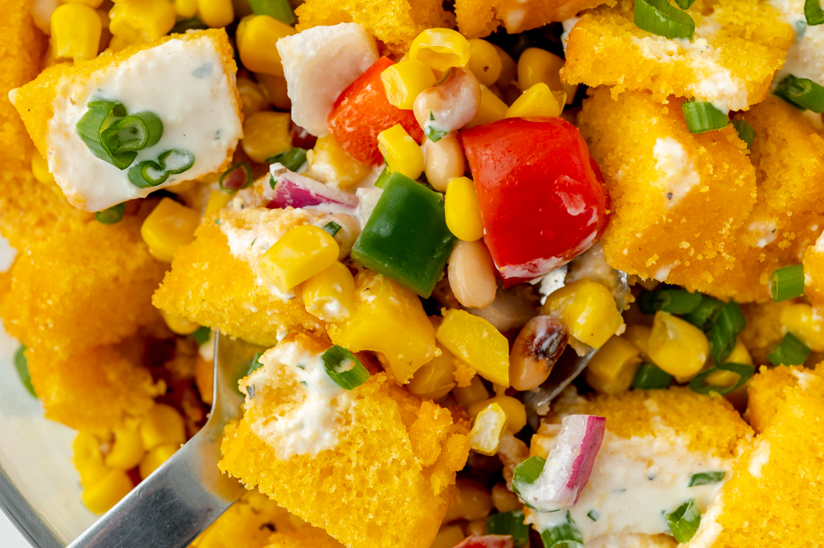 close up overhead shot of serving spoon in bowl of cornbread salad