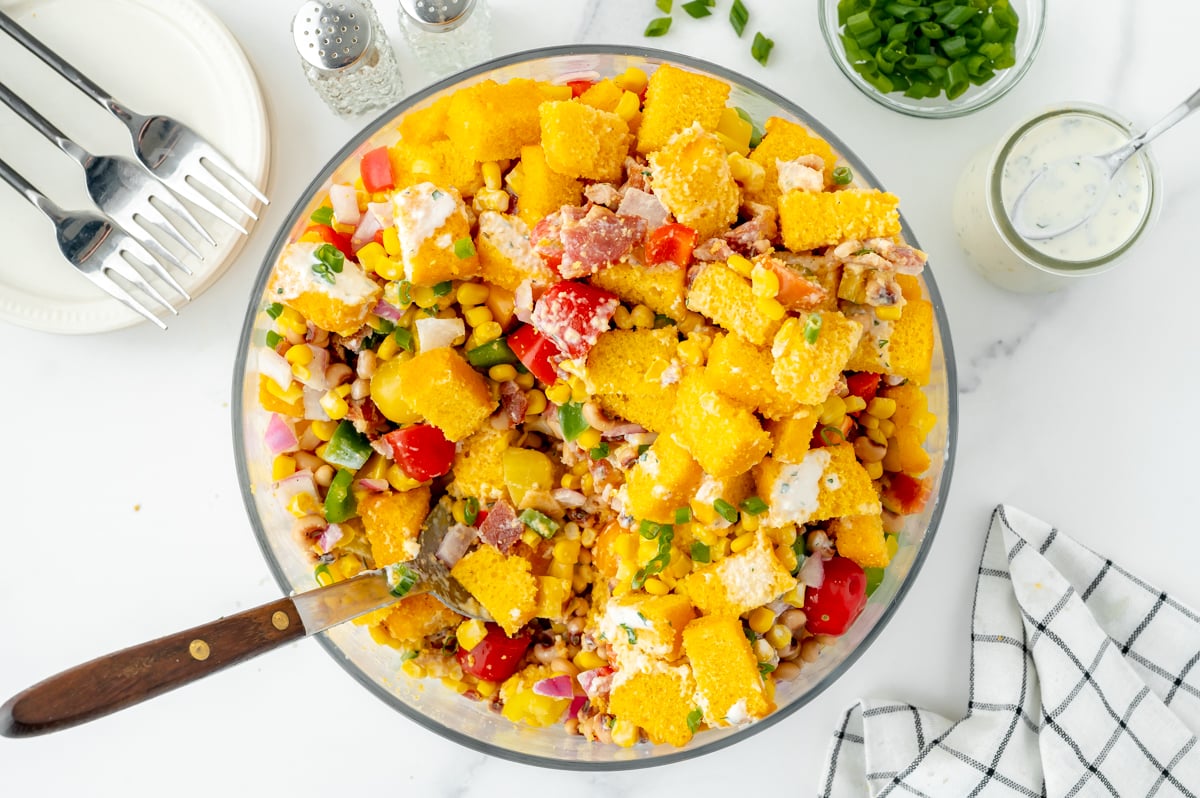 overhead shot of serving spoon in bowl of cornbread salad