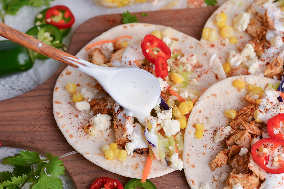 angled shot of spoon adding crema mexico to tacos