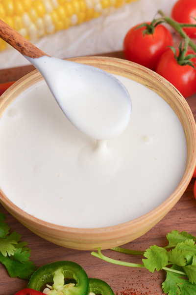 close up angled shot of spoon in bowl of crema mexicana