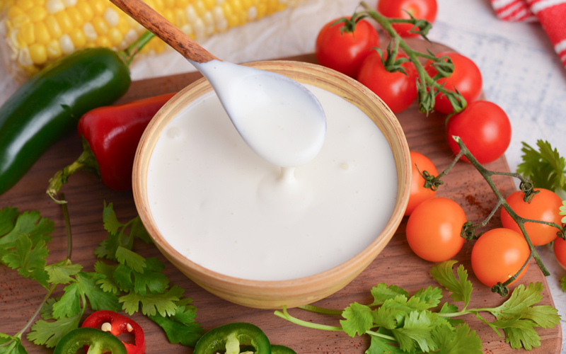 close up angled shot of spoon in bowl of crema mexicana