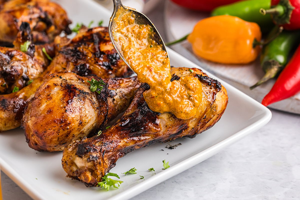 angled shot of spoon adding sauce to peri peri chicken