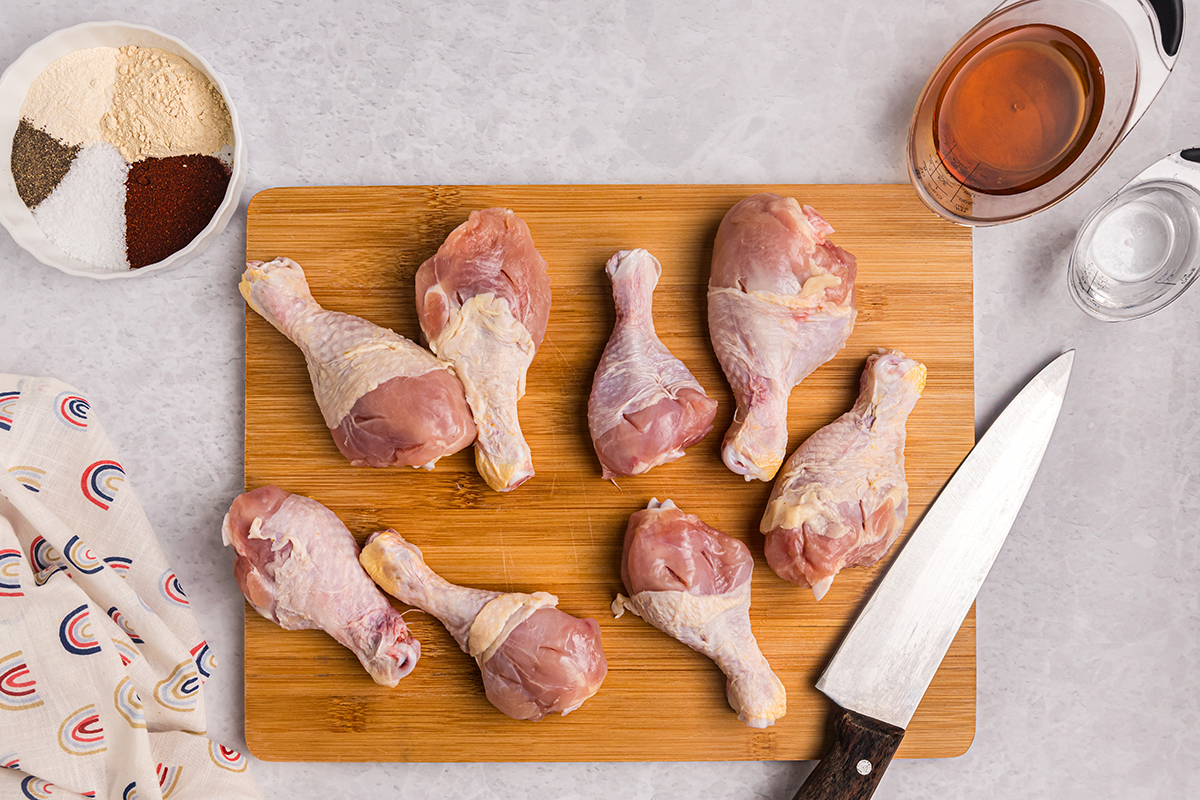 raw chicken drumsticks on a wooden board