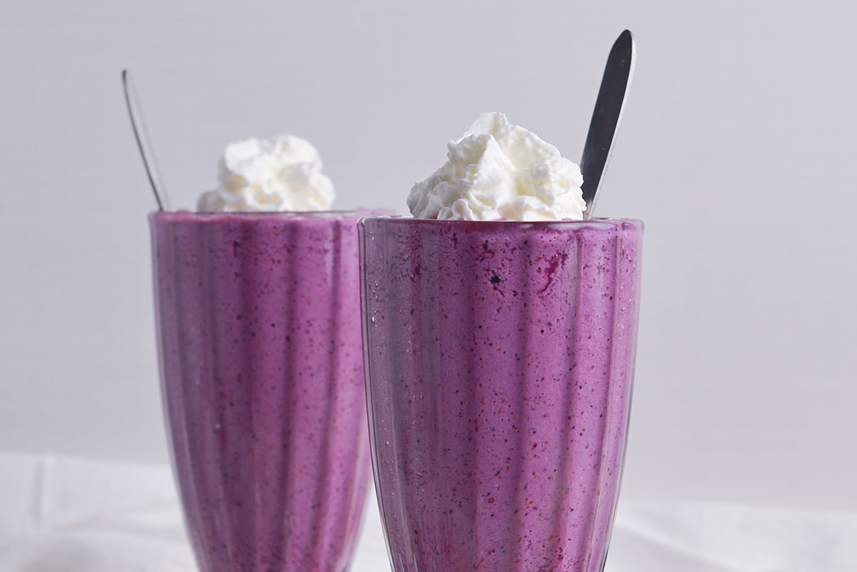 straight on shot of grimace shakes topped with whipped cream