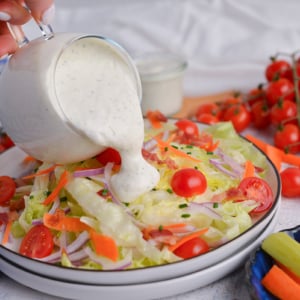 straight on shot of light ranch dressing pouring onto salad