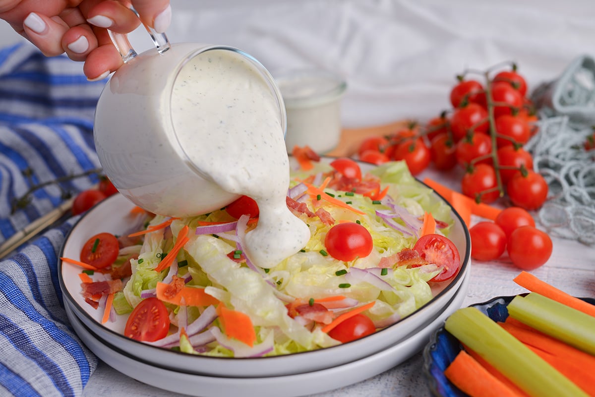 straight on shot of light ranch dressing pouring onto salad