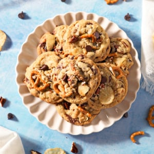 overhead scalloped plate of kitchen sink cookies with pretzels, chocolate chips and potato chips sticking out.
