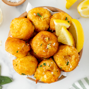 overhead shot of bowl of lemon ricotta fritters with lemons