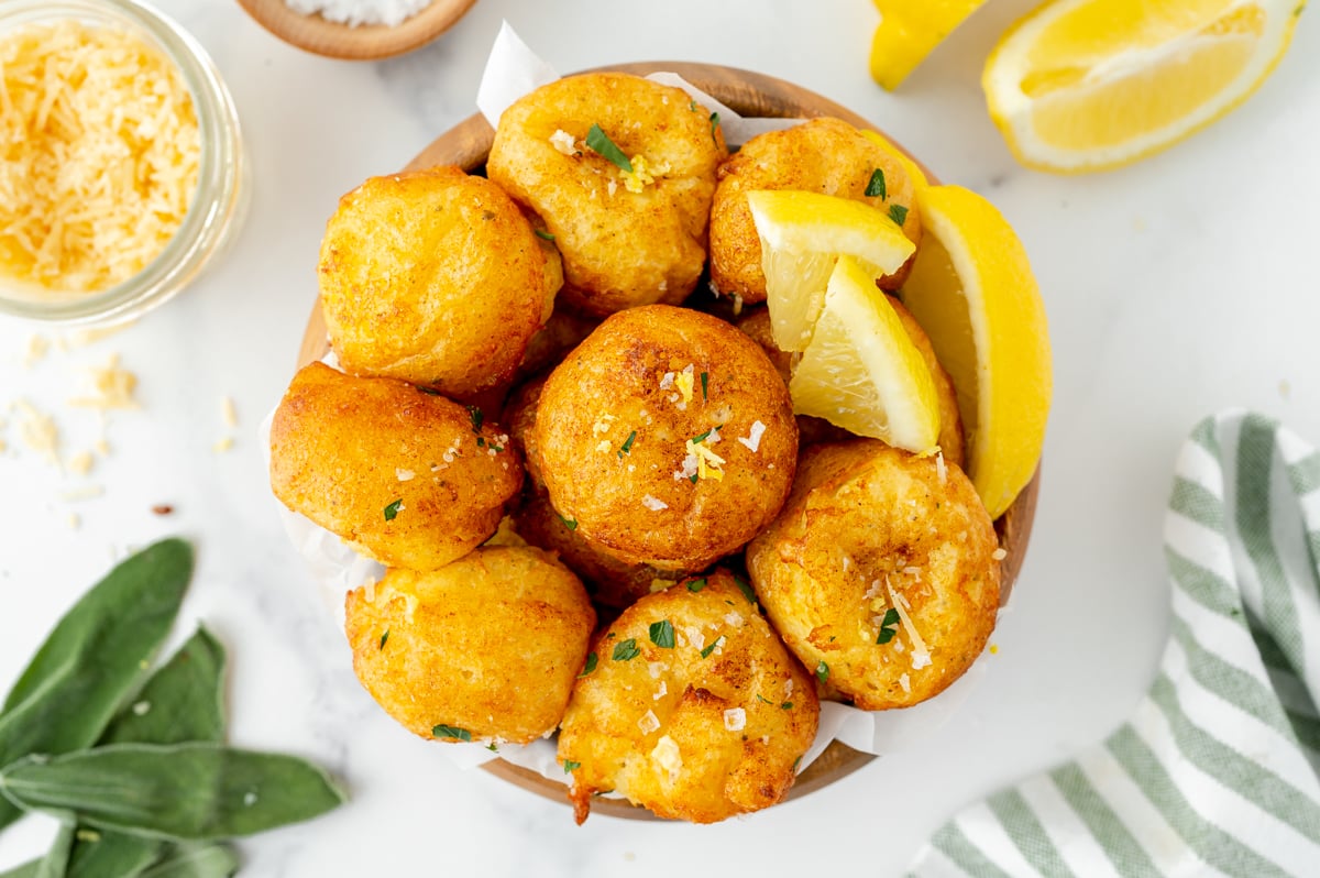 overhead shot of bowl of lemon ricotta fritters with lemons