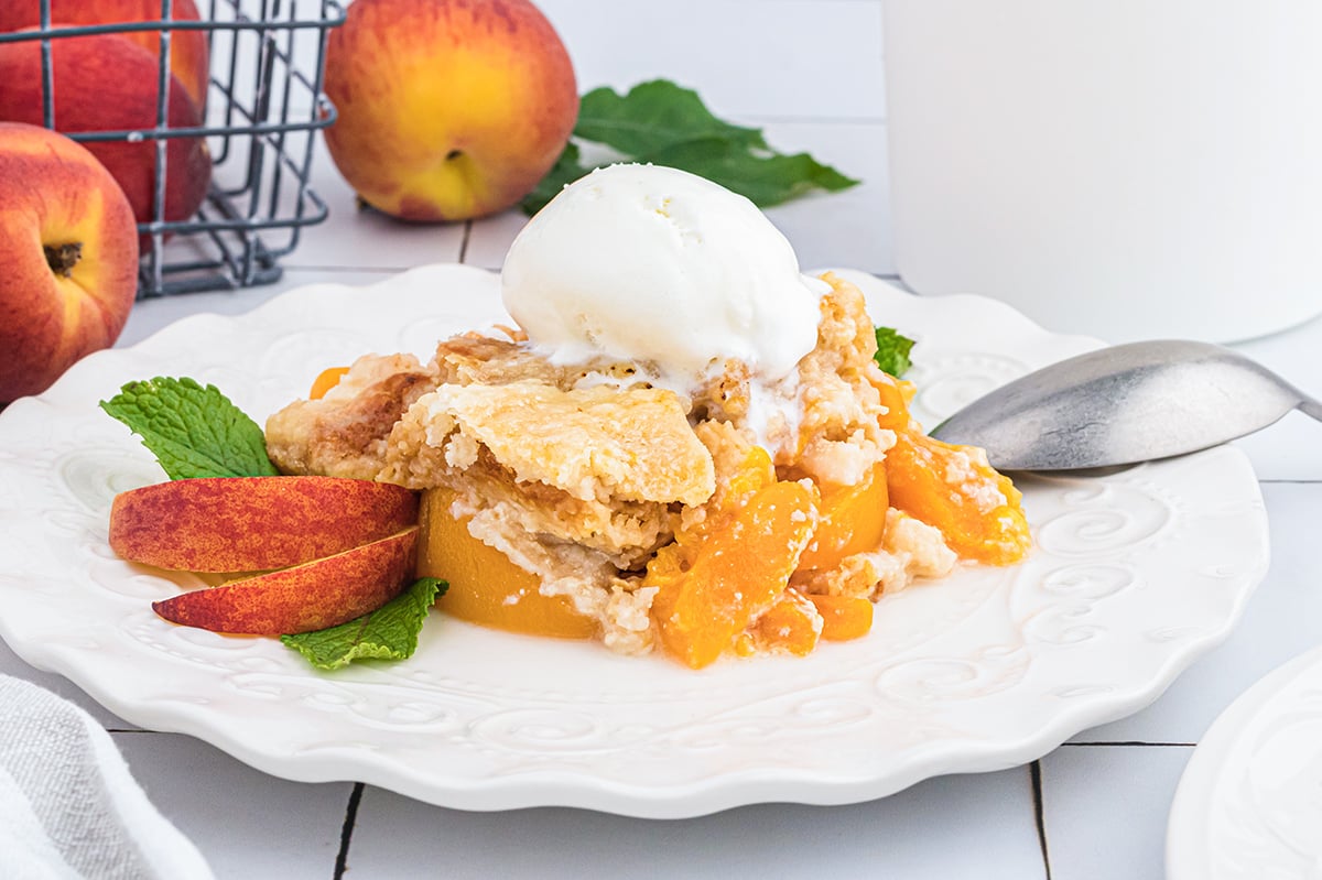straight on shot of peach dump cake on plate topped with ice cream