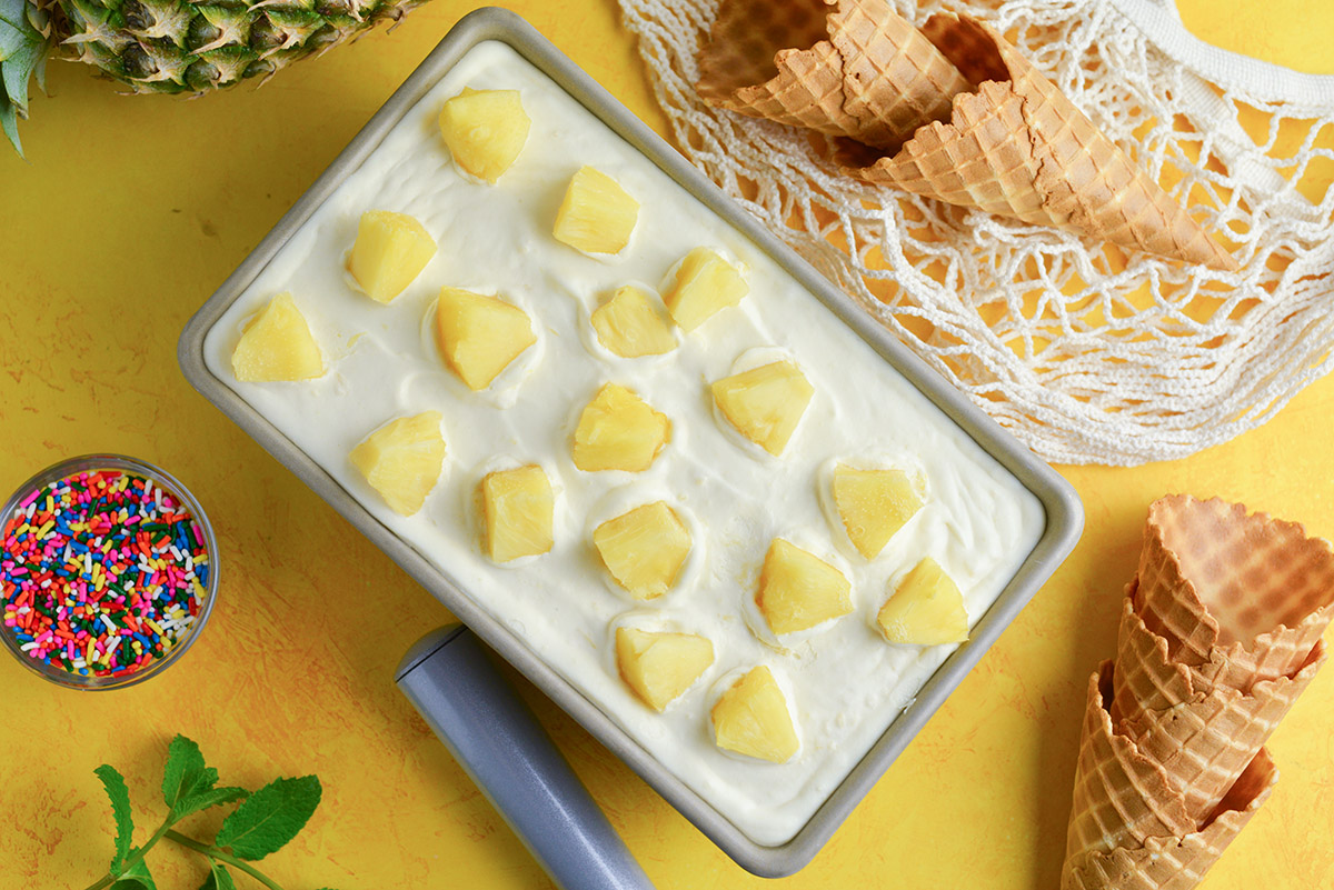 overhead of no churn pineapple ice cream with chunks of pineapple in a loaf pan