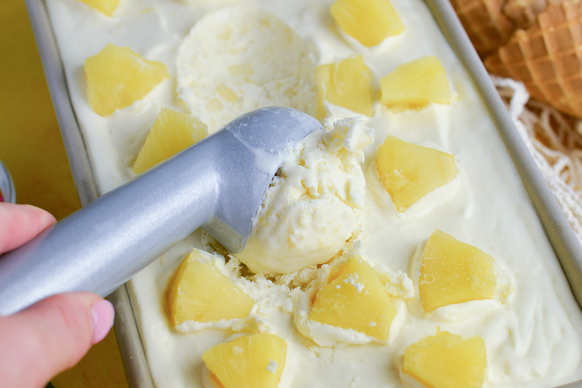 ice cream scoop in a pan of no churn ice cream with pineapples