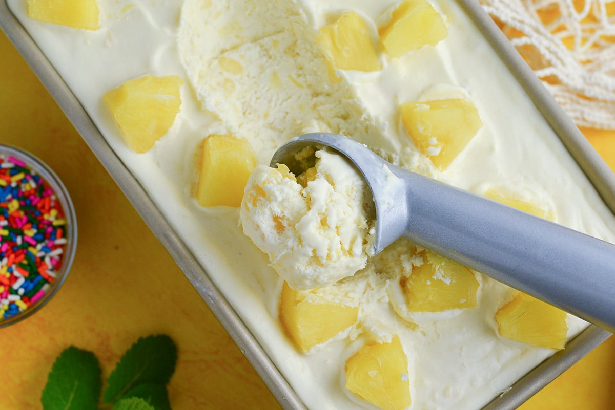 close up of scoop of homemade no churn ice cream with pineapple chunks