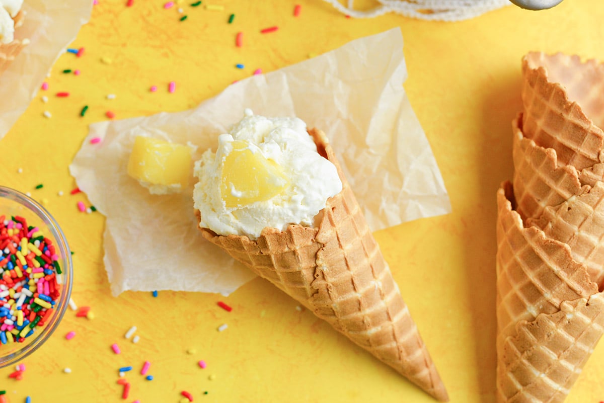 homemade pineapple ice cream in a waffle cone with sprinkles