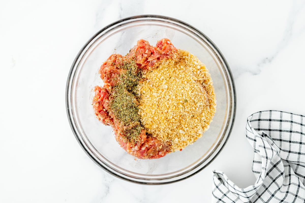 overhead shot of breadcrumbs, italian seasoning and sausage in bowl