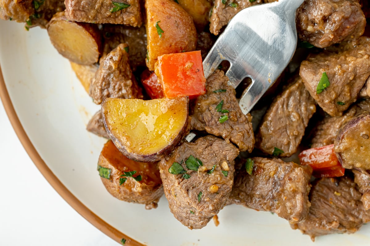 overhead shot of fork full of steak and potatoes