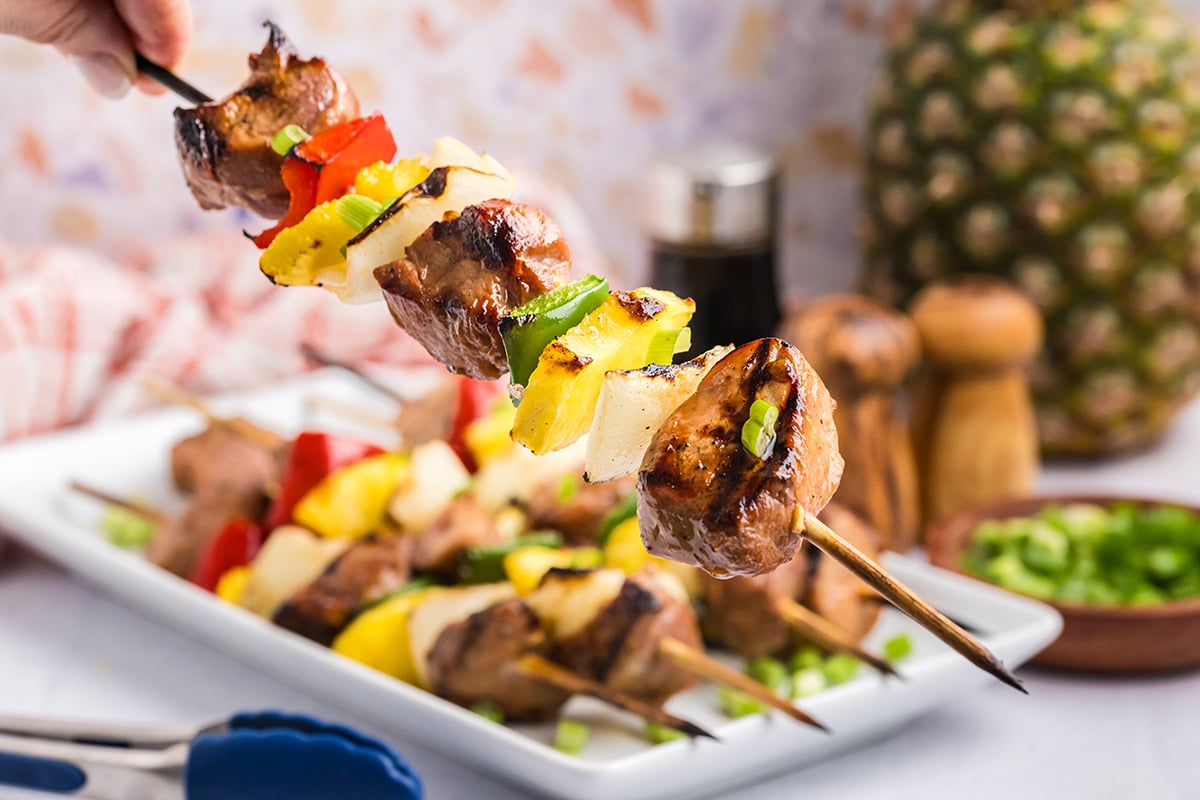 angled shot of hand holding teriyaki pork kabob