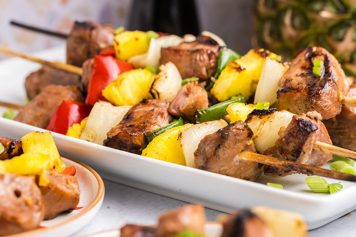 close up angled shot of teriyaki pork kabobs on tray