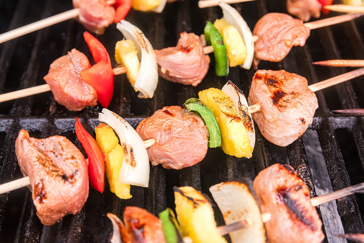 pork kabobs on the grill with assorted vegetables