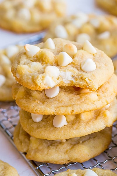 bite taken out of stack of white chocolate chip cookies