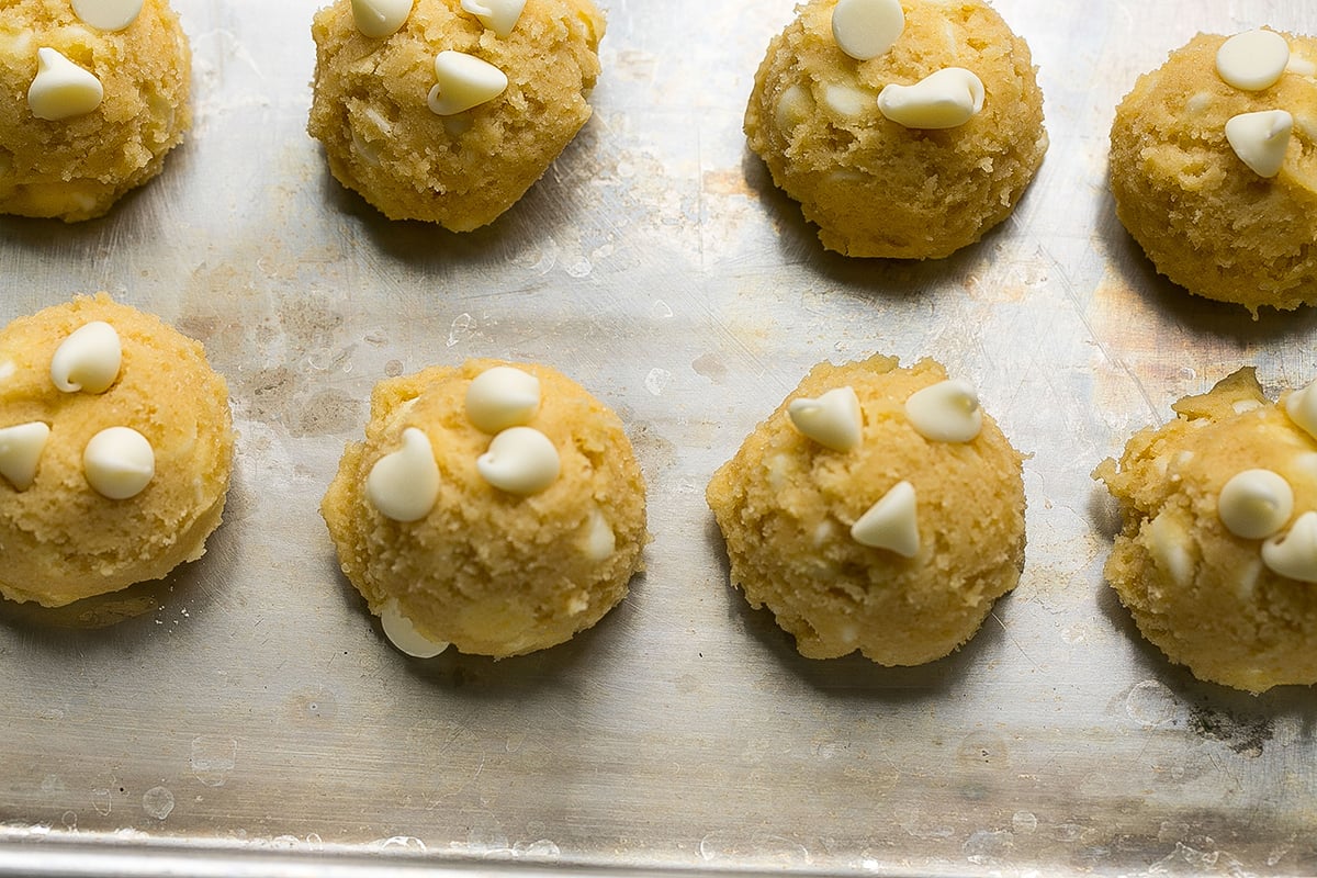 balls of white chocolate chip cookie dough on baking sheet