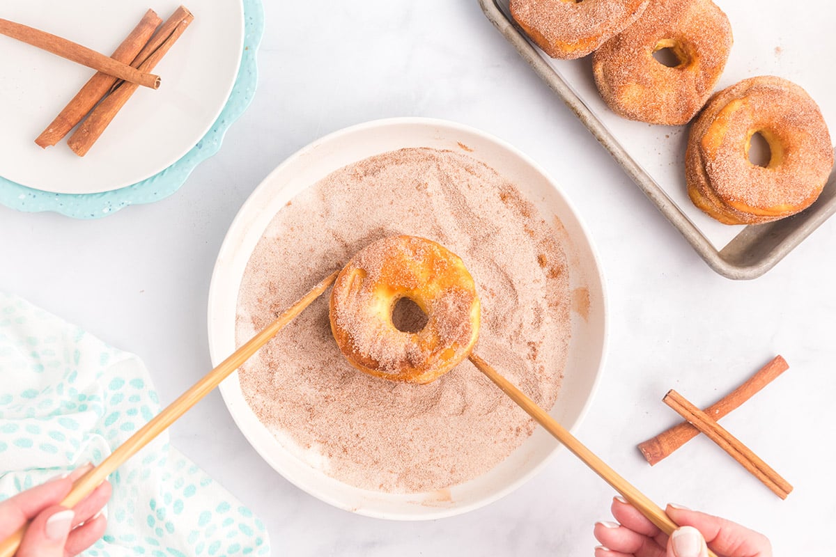 tossing biscuits in cinnamon sugar mixture using chopsticks