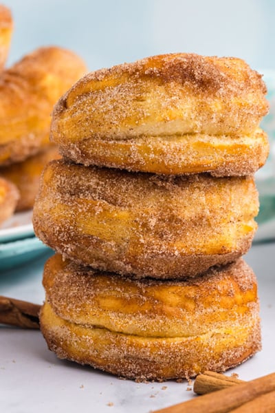 stack of three donuts with bowl of donut holes in the back
