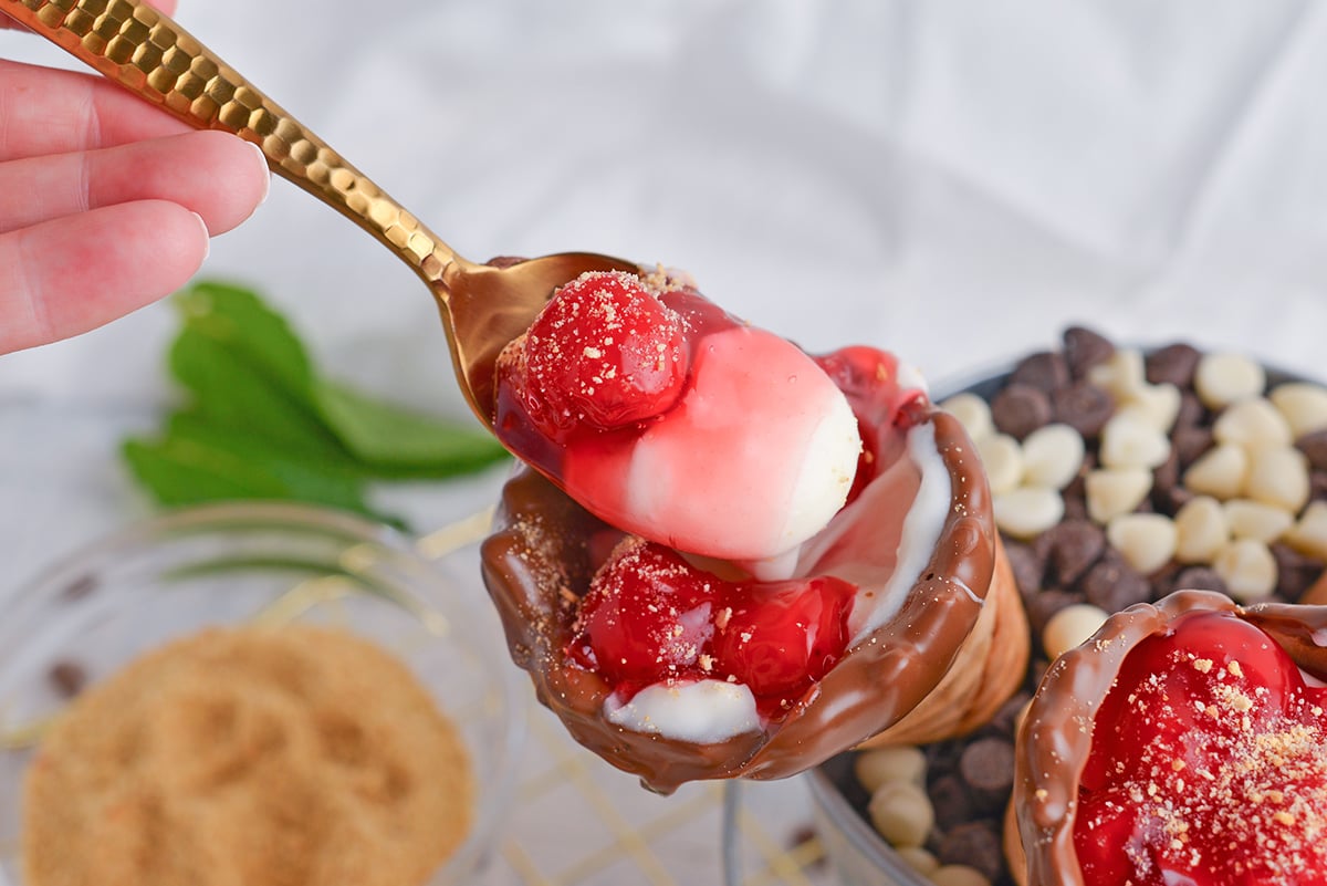 spoon digging into cherry cheesecake cone