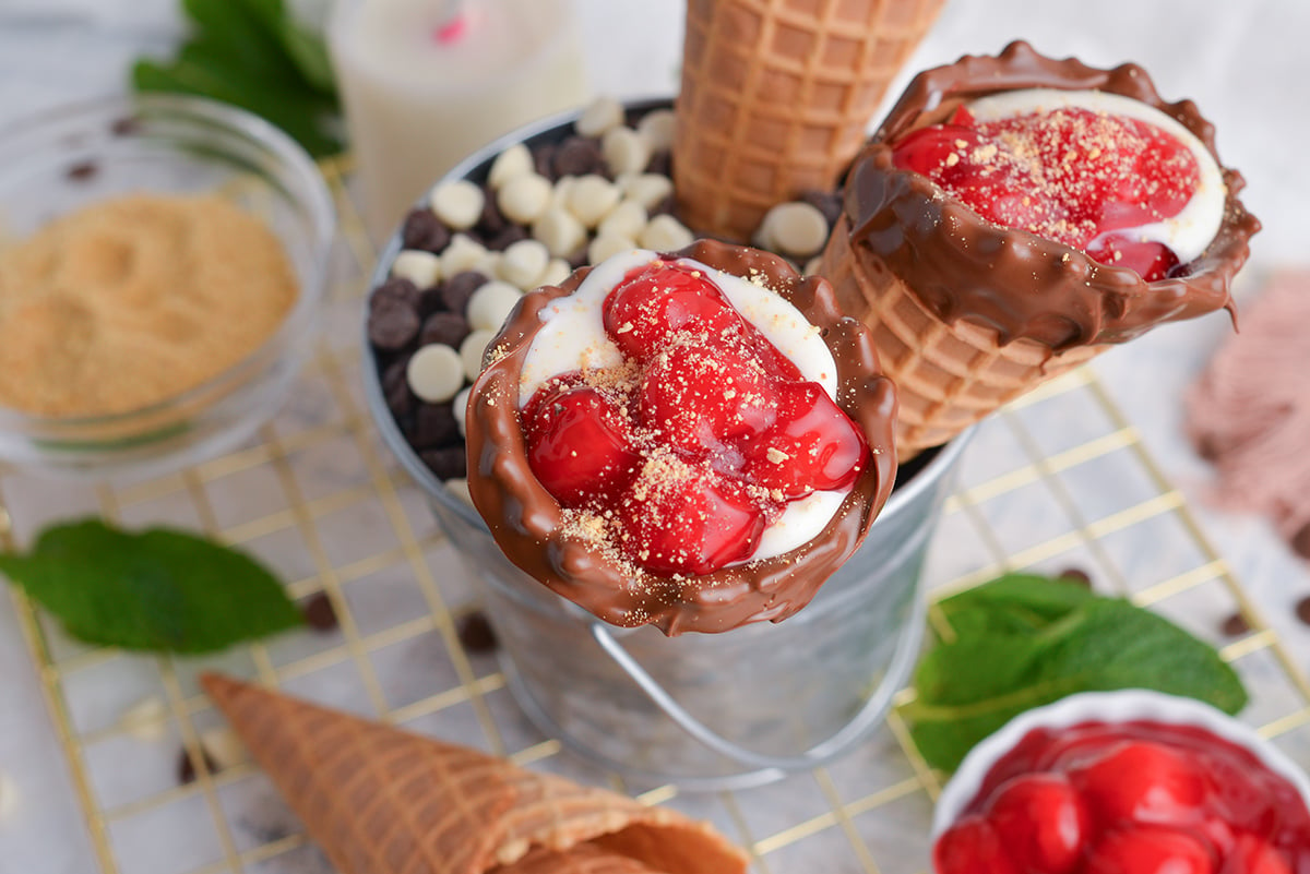 three cherry cheesecake cones in bucket of chocolate chips